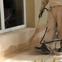 General pest control technician spraying exterior perimeter around a home in Cape Coral, FL