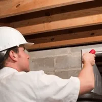 Termite inspection technician checking a basement wall and framing for termite activity in Cape Coral, FL
